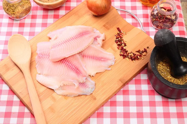 Raw fish tilapia on cutting board and spices — Stock Photo, Image