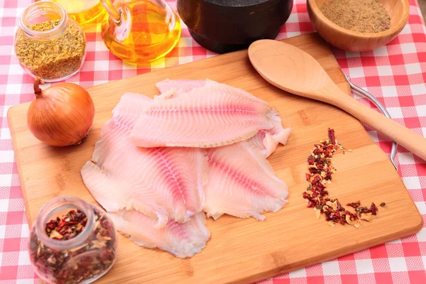 Tilapia de pescado crudo en tabla de cortar y especias —  Fotos de Stock