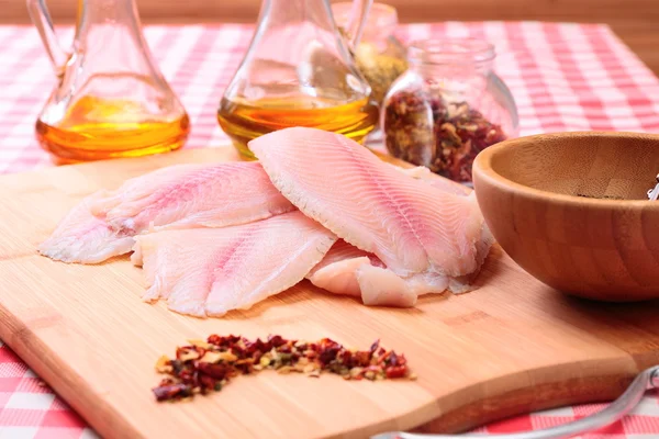 Rå fisk tilapia på skärbräda och kryddor — Stockfoto