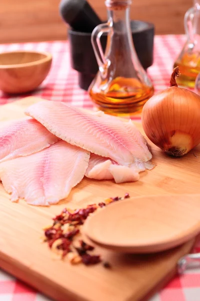 Tilapia di pesce crudo su tagliere e spezie — Foto Stock