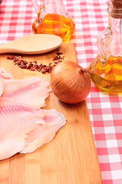Rauwe vis tilapia op snijplank en specerijen — Stockfoto