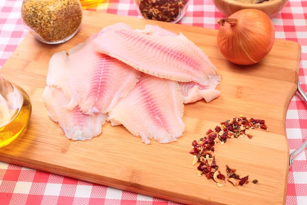 Çiğ balık tilapia kesme tahtası ve baharatlar — Stok fotoğraf