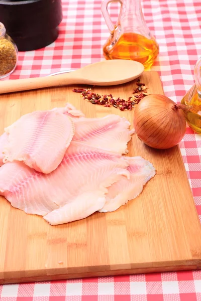 Raw fish tilapia on cutting board and spices — Stock Photo, Image