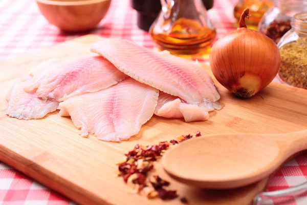 Tilapia de pescado crudo en tabla de cortar y especias —  Fotos de Stock