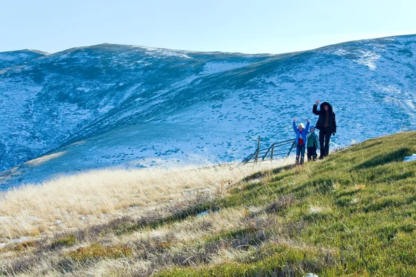 Familjen gå på hösten bergsplatå med första vinter snö — Stockfoto