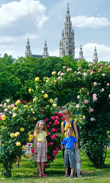 Família perto de arbustos de rosa florescentes . — Fotografia de Stock