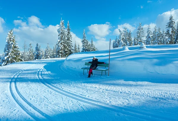 Winter mountain fir forest landscape and woman on bench. — Stockfoto