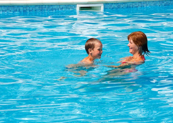 Мать учит своего сына плавать в бассейне . — стоковое фото