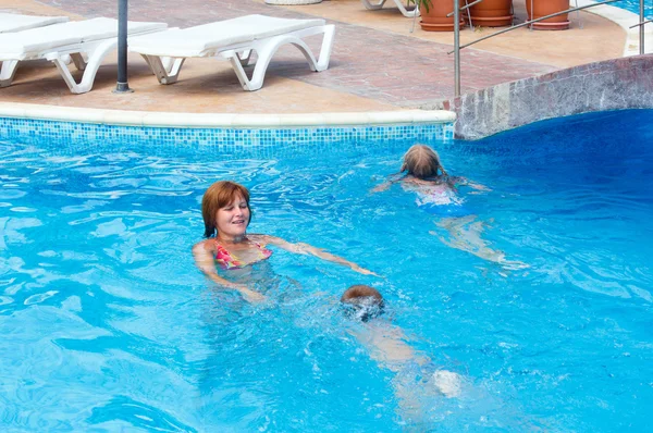 Mutter schult Kinder zum Schwimmen im Pool. — Stockfoto