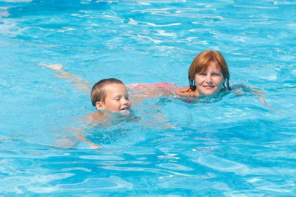 Matka vlak svého syna plavat v bazénu. — Stock fotografie