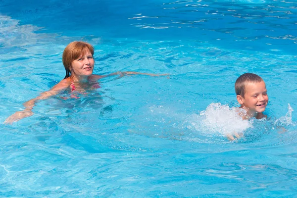 母はプールで泳ぐ彼女の息子を訓練します。. — ストック写真