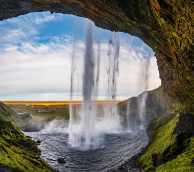 Resimli şelale Seljalandsfoss sonbahar manzarası, güneybatı İzlanda. İnsanlar ve araba tanınmaz halde..