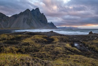 Sunrise Stoksnes Cape Sahili ve Vestrahorn Dağı, İzlanda. İnanılmaz doğa manzarası, popüler seyahat yerleri. Siyah volkanik kum tepelerinde sonbahar otları.