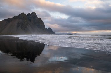Gündoğumu Stoksnes Cape Deniz Sahili ve Vestrahorn Dağı Islak siyah volkanik kum yüzeyi, İzlanda. İnanılmaz doğa manzarası, popüler seyahat merkezi..