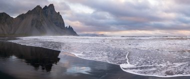 Gündoğumu Stoksnes Cape Deniz Sahili ve Vestrahorn Dağı Islak siyah volkanik kum yüzeyi, İzlanda. İnanılmaz doğa manzarası, popüler seyahat merkezi..