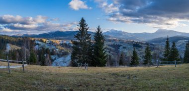 Sonbaharın sonlarında gün batımından önce, tepeleri karla kaplı bir dağ manzarası. Resimli seyahat, mevsimlik, doğa ve kırsal güzellik konsepti. Karpatlar, Ukrayna.