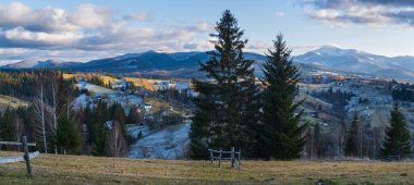 Sonbaharın sonlarında gün batımından önce, tepeleri karla kaplı bir dağ manzarası. Resimli seyahat, mevsimlik, doğa ve kırsal güzellik konsepti. Karpatlar, Ukrayna.