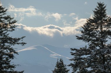Kış uzak dağlık dağ köyü, kırsal tepeler, ağaçlar ve tarım arazileri..