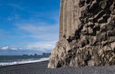 Meşhur Kara Kum Okyanus Sahili, Reynisfjall Dağı ve Picturesque Bazalt Sütunları, Vik, Güney İzlanda. Uzak dirolaey pelerini ve kaya oluşumları.
