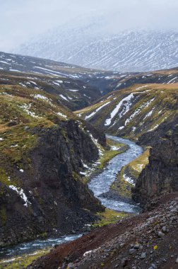 İzlanda 'nın kuzeyinde sonbahar bulutlu bir gün. Güzel kanyondan akan küçük bir nehir.