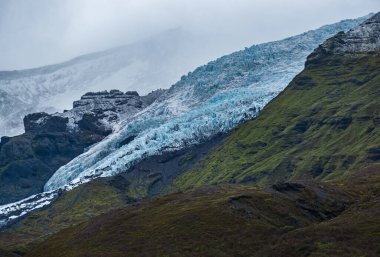 İzlanda 'da otomobil gezisi sırasında otoban manzarası. Manzaralı İzlanda manzarası: hamletler, dağlar, okyanus kıyıları, fiyortlar, tarlalar, bulutlar, buzullar, şelaleler.