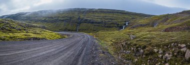 İzlanda 'da otomobil gezisi sırasında çakıl yolu ve dağ manzarası. İzlanda manzaralı muhteşem sonbahar manzarası..