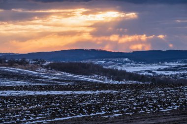 Kara toprak, son karla kaplı ekilebilir arazi, ilkbaharın başlarında. Ukrayna kırsalında sakin bir akşam günbatımı, Lviv bölgesi.