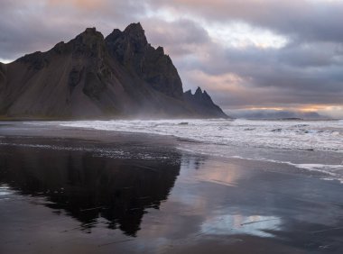 Gündoğumu Stoksnes Cape Deniz Sahili ve Vestrahorn Dağı Islak siyah volkanik kum yüzeyi, İzlanda. İnanılmaz doğa manzarası, popüler seyahat merkezi..