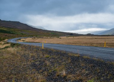 İzlanda 'da otomobil gezisi sırasında çakıl yolu ve dağ manzarası. İzlanda manzaralı muhteşem sonbahar manzarası..