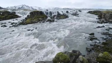Güney İzlanda 'da mevsim değişiyor. Resimli su falı Tungnaarfellsfoss panoramik sonbahar manzarası. Landmannalaugar Dağları karların altında.
