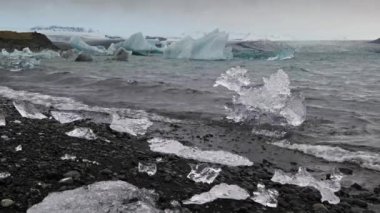 Jokulsarlon Buzul Gölü, İzlanda 'da buzla kaplı bir göl. Breidamerkurjokull buzulu, Vatnajokull buzulu veya Vatna Buzulu 'nun başındaki Atlantik Okyanusu kıyısında. İnsanlar tanınmaz halde..