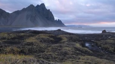 Sunrise Stoksnes Cape Sahili ve Vestrahorn Dağı, İzlanda. İnanılmaz doğa manzarası, popüler seyahat yerleri. Siyah volkanik kum tepelerinde sonbahar otları.