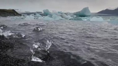 Jokulsarlon Buzul Gölü, İzlanda 'da buzla kaplı bir göl. Breidamerkurjokull buzulu, Vatnajokull buzulu veya Vatna Buzulu 'nun başındaki Atlantik Okyanusu kıyısında. İnsanlar tanınmaz halde..