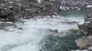 Ukrayna Karpatları 'ndaki Prut nehrinde şelale Probiy üzerinde kar yağışı. Ukrayna 'nın ünlü Yaremche tatil beldesinin göbeğinde yer alıyor. Vahşi Dağ Nehri Taş kayalar ve taş akıntılarıyla akıyor..