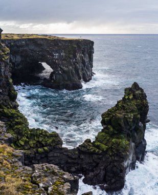Doğu İzlanda, Snaefellsnes yarımadası, Svortuloft Deniz feneri yakınlarındaki Manzara Noktası 'ndaki araba gezisine bakın. Muhteşem siyah volkanik kayalık okyanus kıyıları, mağara kemerleri ve kuleleri..