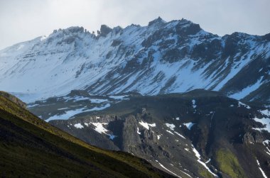 View during auto trip in West Iceland highlands, Snaefellsnes peninsula, Snaefellsjokull National Park. Spectacular volcanic tundra landscape with mountains in clouds.