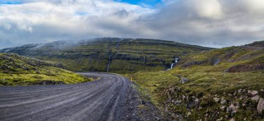 İzlanda 'da otomobil gezisi sırasında çakıl yolu ve dağ manzarası. İzlanda 'nın muhteşem sonbahar manzaralı dağlık arazisi.
