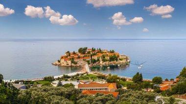 Sveti Stefan deniz adasının sabah manzarası, sahil ve şehir merkezi (Karadağ). İnsanlar, arabalar ve tabelalar tanınmaz halde..