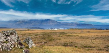 İzlanda 'da otomobil gezisi sırasında görüntüle. Manzaralı İzlanda manzarası: dağlar, okyanus kıyıları, fiyortlar, tarlalar, bulutlar, buzullar, şelaleler.