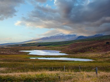 İzlanda 'daki otomobil gezisi sırasında güzel bir dağ manzarası. Manzaralı İzlanda manzarası: dağlar, tarlalar, bulutlar, göller, buzullar.