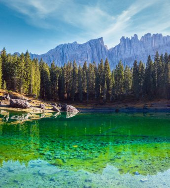 Sunny colorful autumn alpine Dolomites mountain scene, Sudtirol, Italy. Karersee or Lago di Carezza view. Picturesque traveling, seasonal, nature and countryside beauty concept scene.