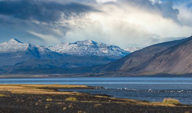 İzlanda 'da otomobil gezisi sırasında görüntüle. Manzaralı İzlanda manzarası: dağlar, okyanus kıyıları, fiyortlar, tarlalar, bulutlar, buzullar, şelaleler, vahşi kuş sürüleri.