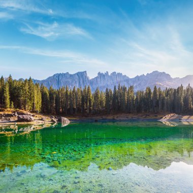 Sunny colorful autumn alpine Dolomites mountain scene, Sudtirol, Italy. Karersee or Lago di Carezza view. Picturesque traveling, seasonal, nature and countryside beauty concept scene.