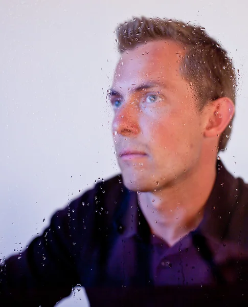 Мужчина смотрит в мокрое окно — стоковое фото