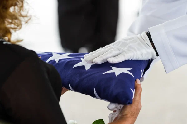 Militär begravning, lämna flagg till änkan Stockbild