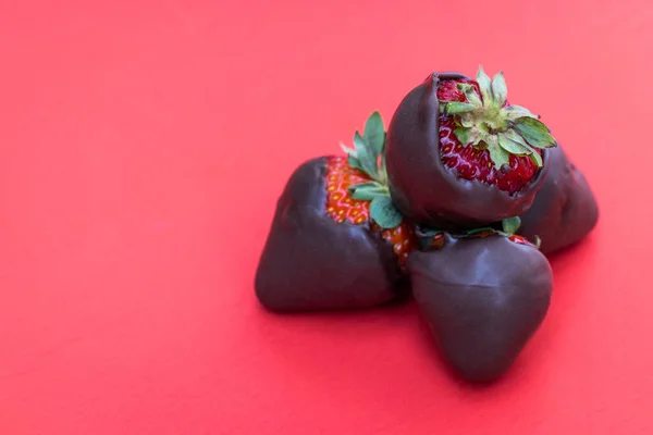 チョコレートで覆われたイチゴは赤い背景に隔離され — ストック写真