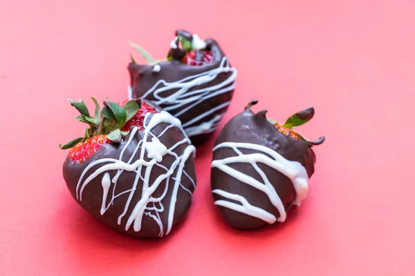 chocolate covered strawberries with a white chocolate swirl isolated on a red background