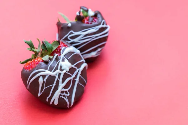 chocolate covered strawberries with a white chocolate swirl isolated on a red background