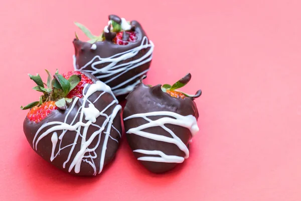 chocolate covered strawberries with a white chocolate swirl isolated on a red background