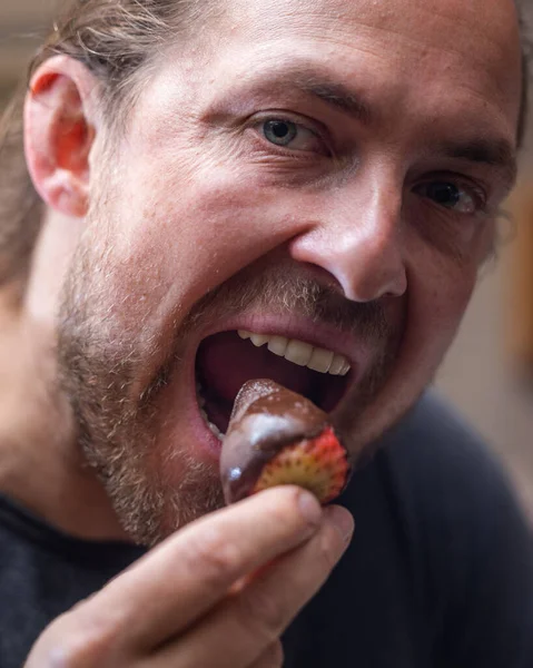 Man eating a chocolate covered strawberry close up portrait